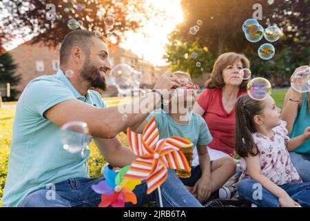 La famiglia soffia le bolle insieme al parco Foto Stock
