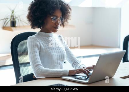 Giovane donna d'affari che lavora su un notebook in ufficio Foto Stock