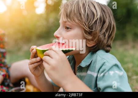 Ragazzo che mangia cocomero al parco Foto Stock