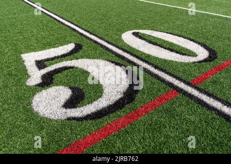 Erba sintetica inclinato calcio linea 50 yard in bianco con ombra nera con linea rossa lacrosse e linea gialla calcio medio campo Foto Stock