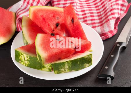 Fette triangolari di anguria sul piatto su fondo nero ardesia. Foto Stock