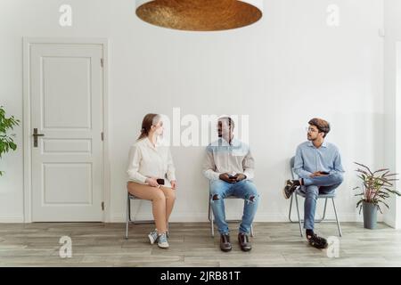 Persone che aspettano e parlano nell'area d'attesa Foto Stock