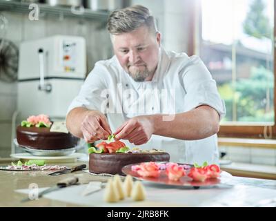 Pasticciere decorazione torta in cucina Foto Stock