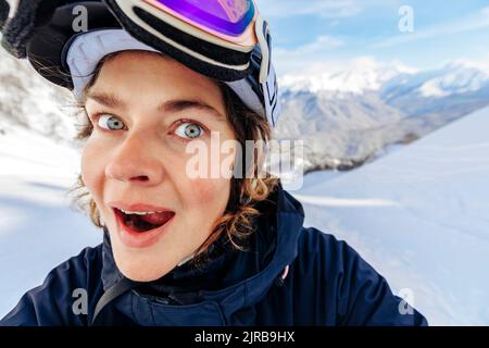 Donna sorpresa di fronte alle montagne innevate Foto Stock