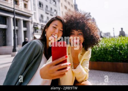 Donna che prende selfie con un amico tramite smartphone Foto Stock