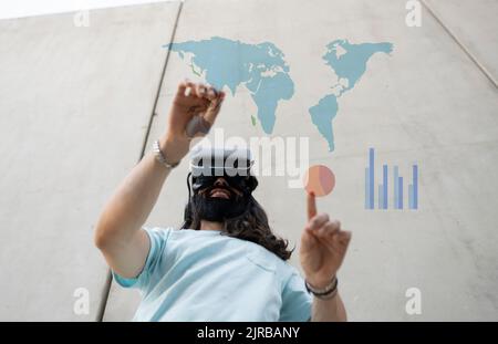 Uomo sorridente che indossa occhiali VR che toccano mappe e carte Foto Stock