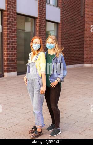 Giovani amici che indossano una maschera protettiva sul sentiero Foto Stock