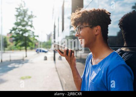 Uomo sorridente che parla con il telefono con vivavoce Foto Stock