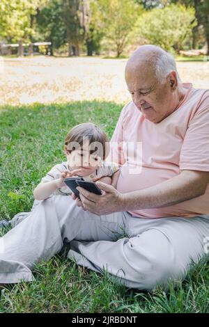 Nonno con nipote che usa lo smartphone al parcheggio Foto Stock