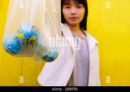 Giovane donna che mostra globi in sacchetto di polietilene Foto Stock