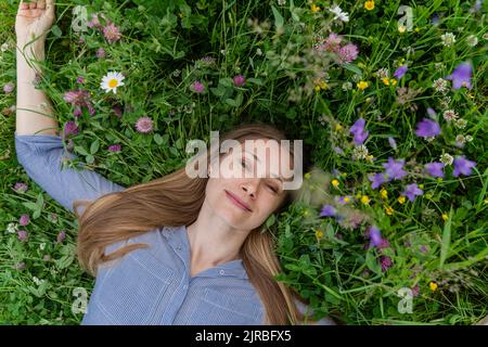 Donna matura felice sdraiata sull'erba in campo Foto Stock