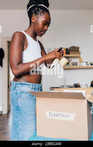 Donna con nastro adesivo imballaggio confezione donazione a letto Foto Stock