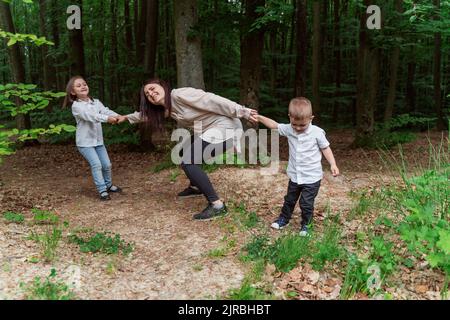 I bambini che tirano la madre che si divertono nella foresta Foto Stock