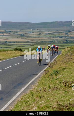 7 agosto 22 Gower Swansea Wales UK Triathlon Ironman evento ciclistico Vista frontale di un singolo file dei ciclisti su una sezione piatta in cima alla collina che si sposta verso la fotocamera. Foto Stock