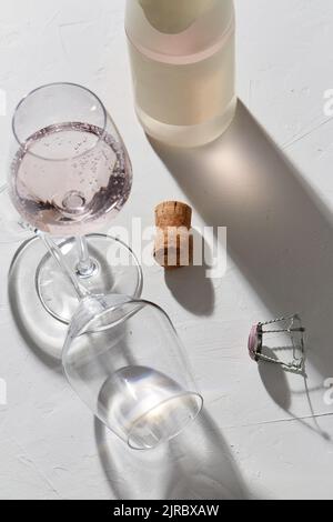 bicchieri da vino e bottiglia di champagne che cade all'ombra Foto Stock