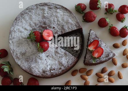 Torta caprese tagliata a fette. Torta al cioccolato e alle mandorle. Una torta squisita e senza farine al cioccolato dell'isola di Capri. Cosparso di zucchero in polvere. Foto Stock