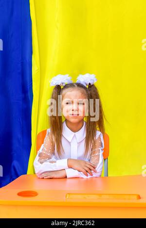 Lysychansk, Ucraina. 1 settembre 2021 - una ragazza con due code di ponytail, archi bianchi e una blusa bianca guarda la macchina fotografica e sorride durante il Foto Stock