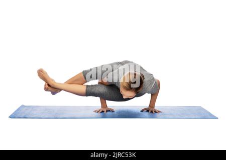 donna che fa yoga in stand mano sul tappetino Foto Stock