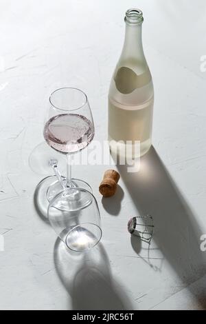 bicchieri da vino e bottiglia di champagne che cade all'ombra Foto Stock