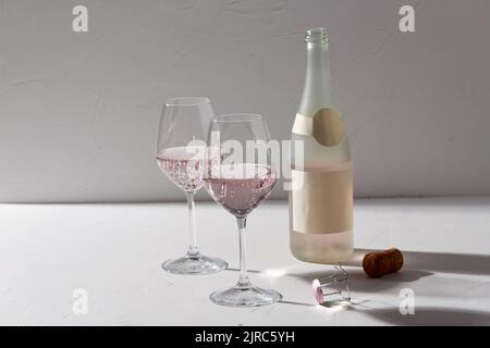 bicchieri da vino e bottiglia di champagne che cade all'ombra Foto Stock