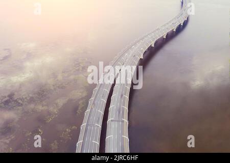 Autostrada ad alta velocità, strada trafficata, il ponte sul fiume baia mare. Vista dall'alto dell'antenna Foto Stock