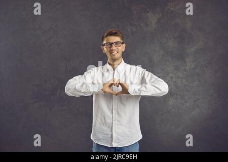 Felice giovane che fa un segno di cuore per mostrare amore e sostegno e per dire grazie Foto Stock