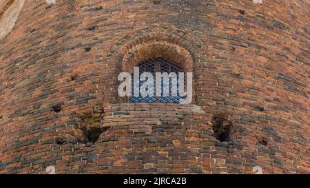 vecchia finestra nel castello, con barre in un vecchio muro di mattoni Foto Stock