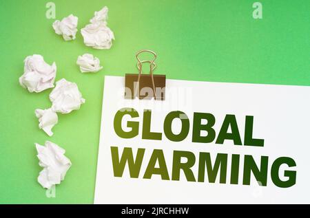 Concetto di ecologia. Su sfondo verde, carta stropicciata e un foglio con l'iscrizione - riscaldamento globale Foto Stock