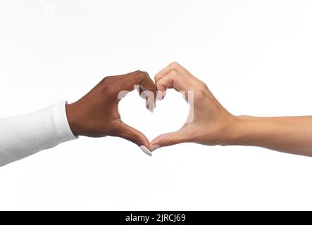 mani bianche e nere che fanno il gesto del cuore Foto Stock