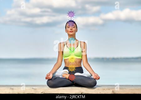 donna meditante in posa loto con sette chakra Foto Stock