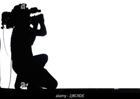 Professione di videografo. Silhouette di un uomo con una fotocamera che scatta un video su sfondo bianco Foto Stock