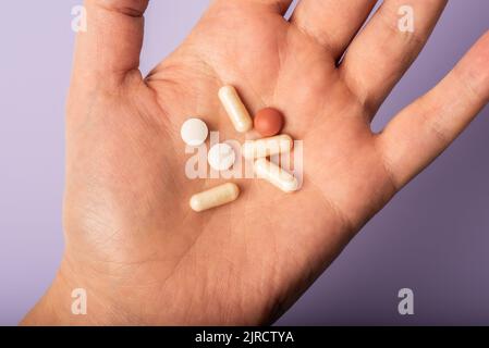 Mano che tiene pillole di vitamina, supplementi nel palmo della mano, medicina Foto Stock