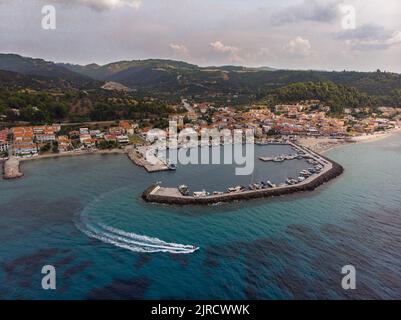 Ripresa aerea del motoscafo che parte dal porto di Nea Skioni e dalla spiaggia di Halkidiki, Grecia, in una giornata di sole con mare azzurro Foto Stock