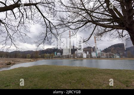 Torre di raffreddamento e camino di centrale termica con denso fumo bianco e grigio che sale nel cielo Foto Stock