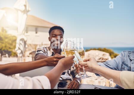 Festeggiamenti, alcolici e amici brindano con vino in un ristorante all'aperto, felice e divertente. Giovani persone diverse che si riuniscono per celebrare la libertà Foto Stock