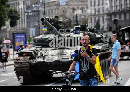 Un uomo in una T-shirt con il simbolo dello stemma ucraino e tenendo la bandiera Ucraina parla al telefono vicino alle attrezzature distrutte dell'esercito russo mostrate a Khreshchatyk nel centro di Kyiv. Come dedicato alla prossima Giornata dell'Indipendenza dell'Ucraina, e quasi 6 mesi dopo l'invasione su larga scala dell'Ucraina il 24 febbraio, la capitale del paese Kyiv tiene una mostra sulla strada principale di Khreshchatyk Street che mostra le attrezzature militari distrutte multiple, carri armati, E le armi delle forze armate della Federazione Russa (AFRF). Come la piena invasione russa dell'Ucraina ha cominciato Foto Stock