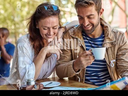 Ci vuole un minuto per assaggiare la birra locale. Una coppia di turisti che pianifica la giornata mentre si prende un caffè in un caffè sul marciapiede. Foto Stock