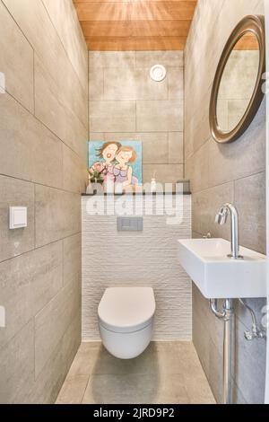 Lavandino base armadio e specchio in bagno piastrellato bianco con WC appeso a parete Foto Stock