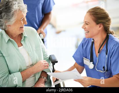 I trattamenti vanno meglio del previsto. Una donna allettante che discute i trattamenti con la sua paziente anziana in sedia a rotelle nel Foto Stock