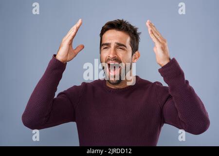 E' stata una mossa terribile. Studio shot di un bel giovane che guarda con rammarico su uno sfondo grigio. Foto Stock