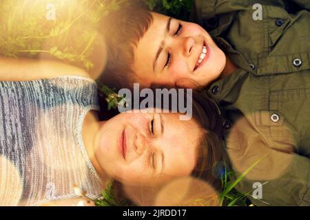 Sogni d'estate felici. Due fratelli carini sdraiati fianco a fianco sull'erba esterna. Foto Stock