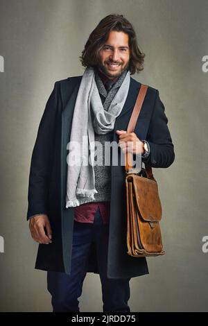 Osate essere ben vestiti. Ritratto di un uomo elegantemente vestito in posa con una borsa a mano in pelle in studio. Foto Stock