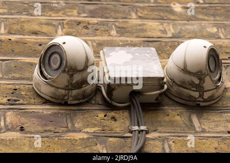 Primo piano di due telecamere CCD di sorveglianza bianche sporche montate sulla facciata, che guardano come il concetto di monitoraggio degli occhi videosorveglianza di sicurezza Foto Stock