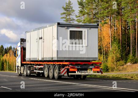 L'autocarro trasporta la cabina portatile su un rimorchio a pianale lungo l'autostrada 2 in un giorno di sole d'autunno, vista posteriore. Lohja, Finlandia. Ottobre 16, 2020. Foto Stock