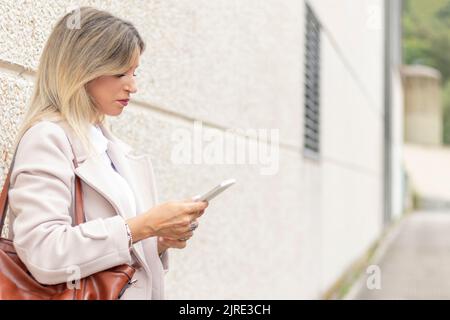 Giovane donna bionda utilizzando il telefono cellulare Foto Stock