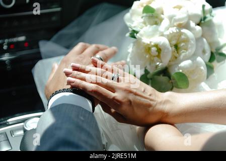 Sposi novelli che tengono le mani, che tengono le mani in primo piano, primo piano delle mani di giovane coppia con anelli di nozze sulle barrette dell'anello Foto Stock