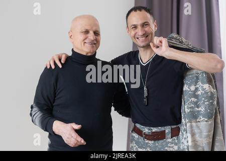 Il padre militare abbraccia suo figlio quando si riunì dopo una missione Foto Stock