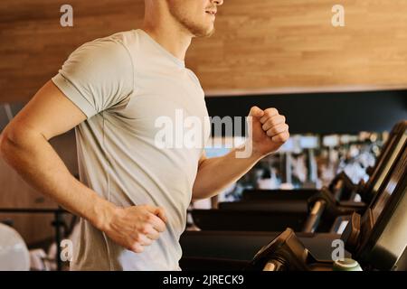 Primo piano di un giovane che corre sul tapis roulant durante l'allenamento nel centro benessere Foto Stock