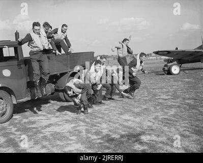 I piloti di n. 19 Squadron RAF tappa una simulazione di 'scramble' dal retro di un carrello a Fowlmere vicino a Duxford, settembre 1940. I piloti della n. 19 Squadron, Royal Air Force 'scramble' per il fotografo, dal retro di un autocarro a Fowlmere, Cambridgeshire. Foto Stock