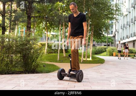 Persona che corre un hoverboard su un sentiero pubblico, ora sono vietati in tutti i luoghi pubblici Foto Stock